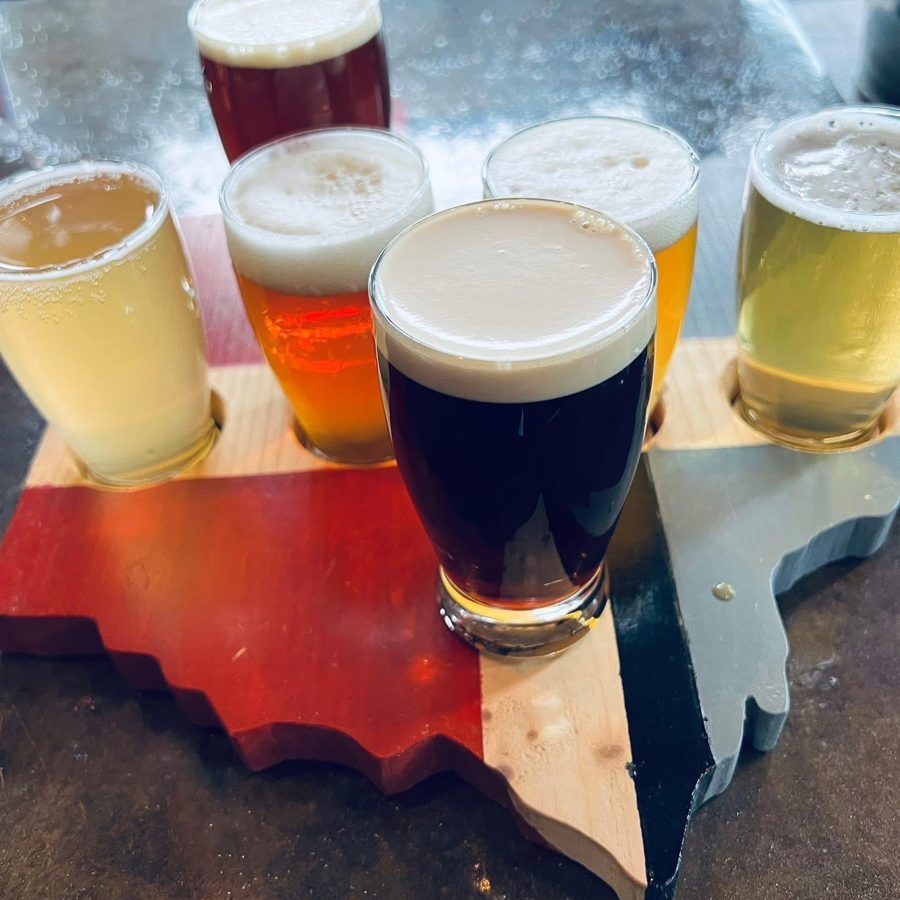 A wooden flight paddle holding six varieties of craft beer